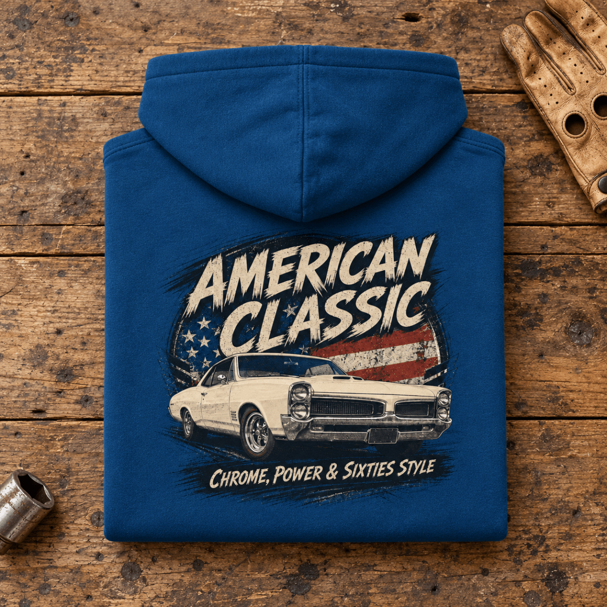 Camberline American Classic 1960s White Muscle Coupe Graphic Hoodie in sapphire blue, folded back view on a workshop bench with the full graphic visible