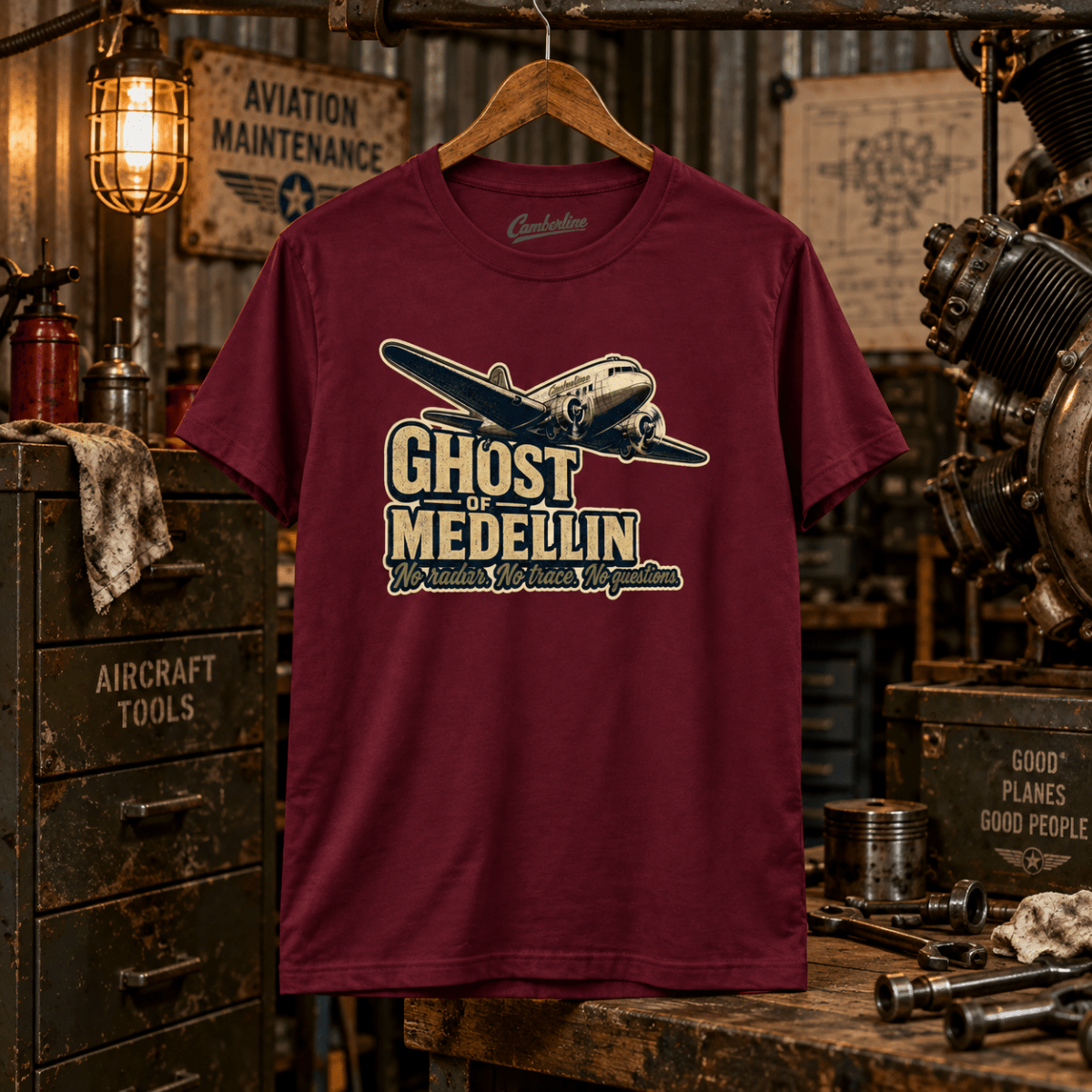 Burgundy Ghost of Medellin DC-3 T-shirt in a gritty vintage aircraft workshop