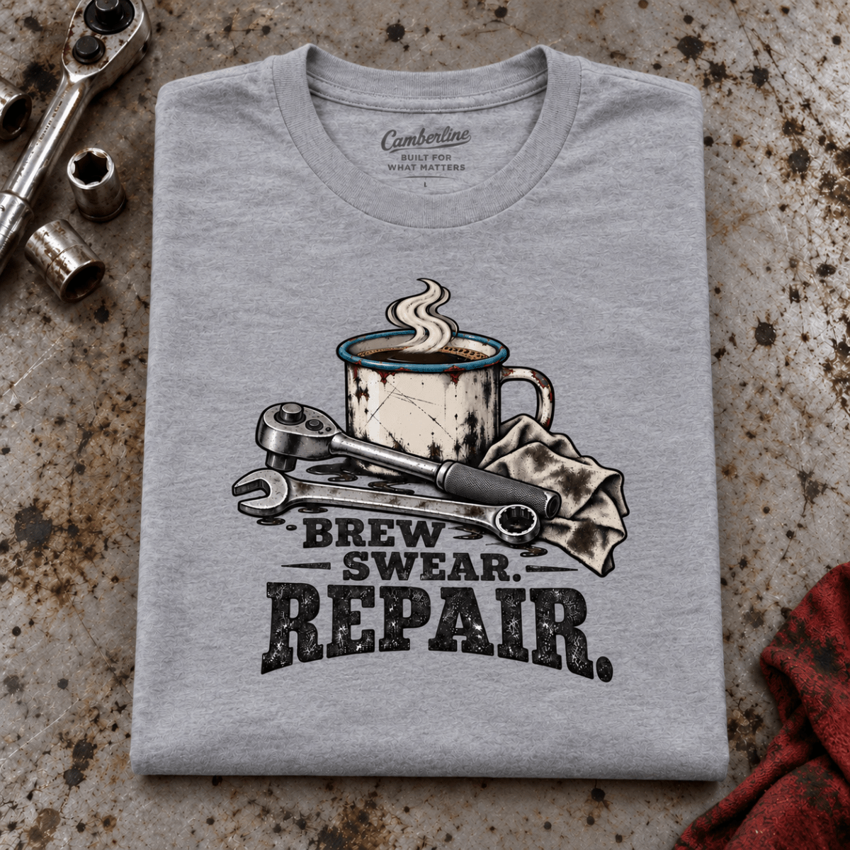 Camberline Coffee and Tools Mechanic T-Shirt in heather grey, folded front view on a workshop bench with full graphic visible
