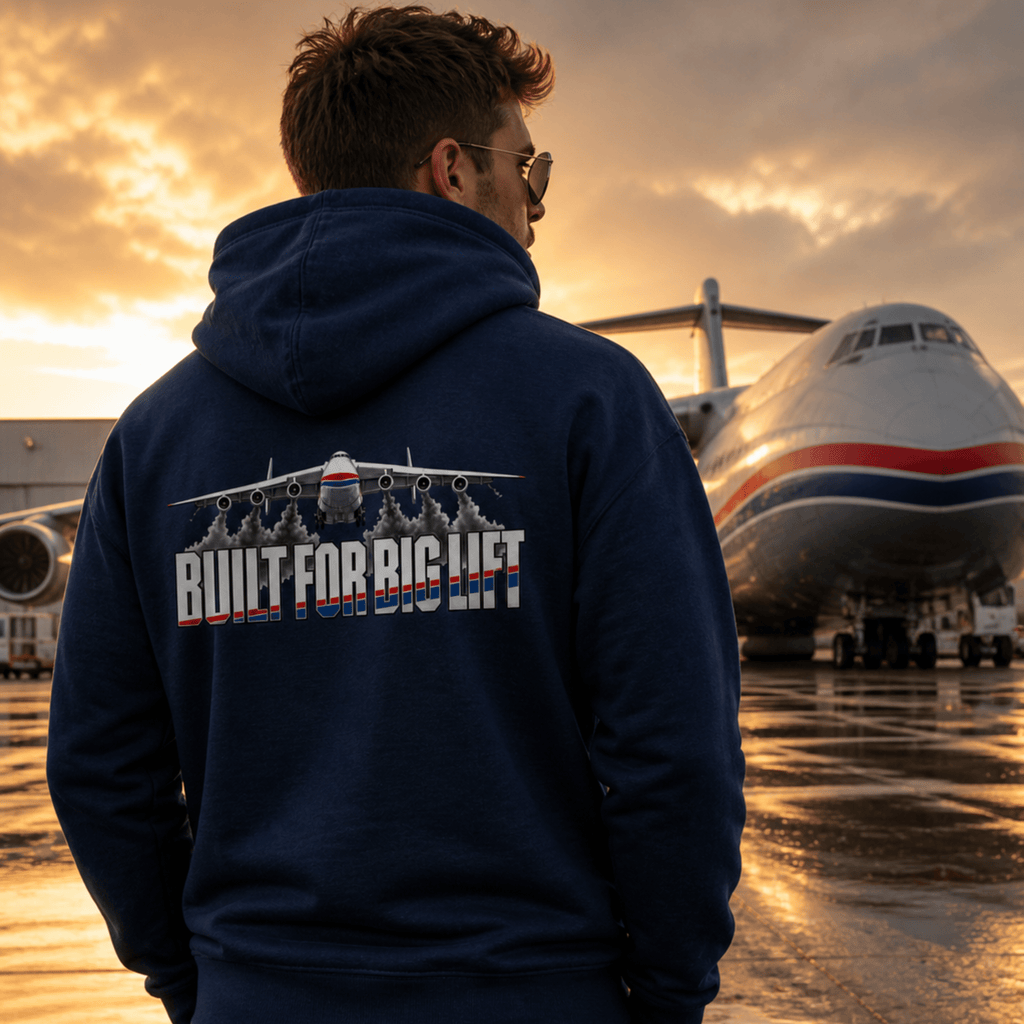 Person wearing a hoodie with 'Built for Big Lift' text in front of an airplane at sunset.