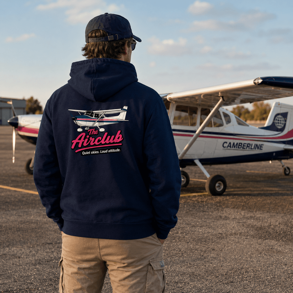 Person wearing a hoodie with 'The Airclub' logo in front of a small airplane.