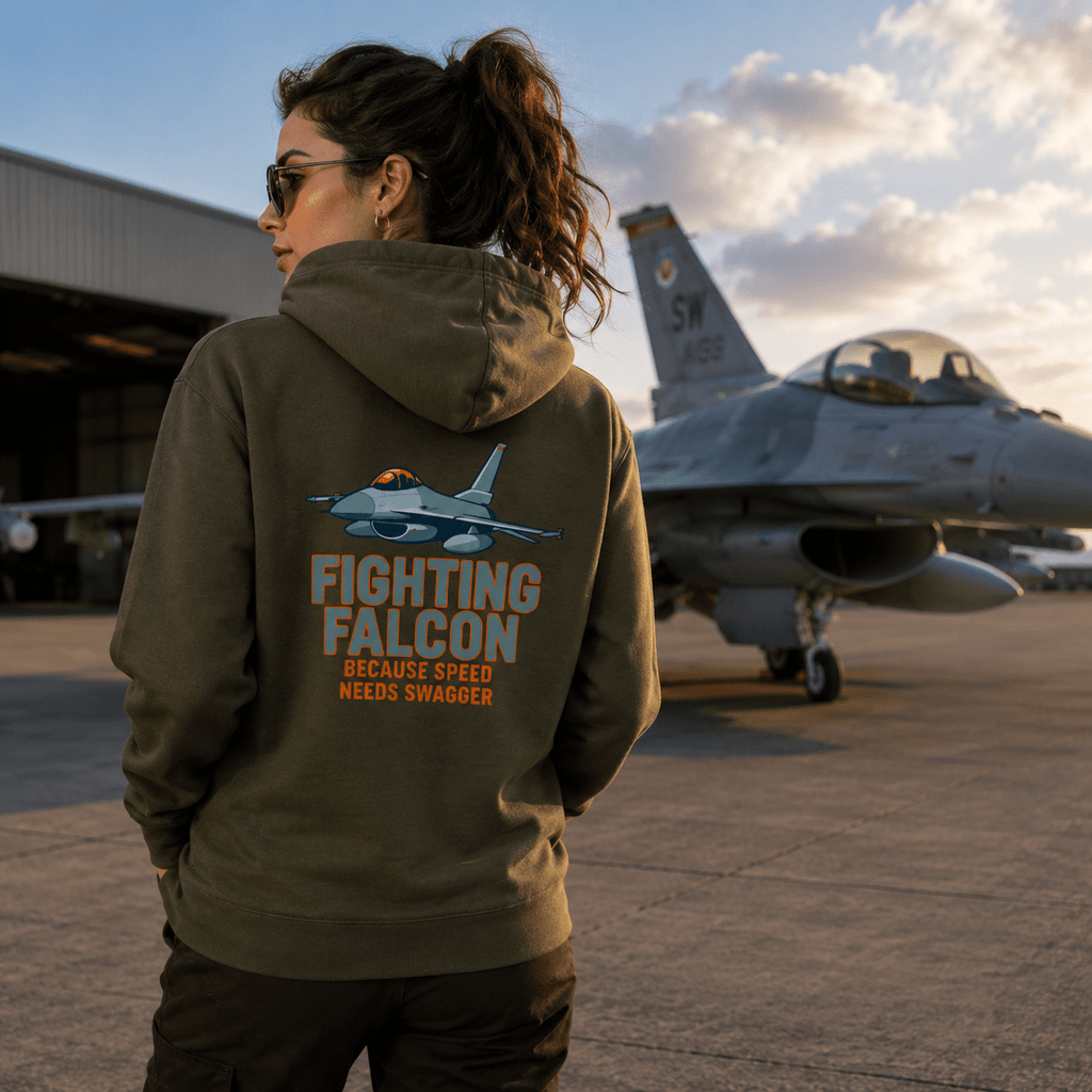 Person wearing a hoodie with 'Fighting Falcon' design in front of a fighter jet on an airfield.