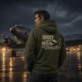 Man wearing a hoodie with 'Ghost of Medellin' design standing in front of an airplane on a runway.