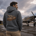 Man wearing a hoodie with 'Hurricane' branding in front of an airplane on a cloudy day.