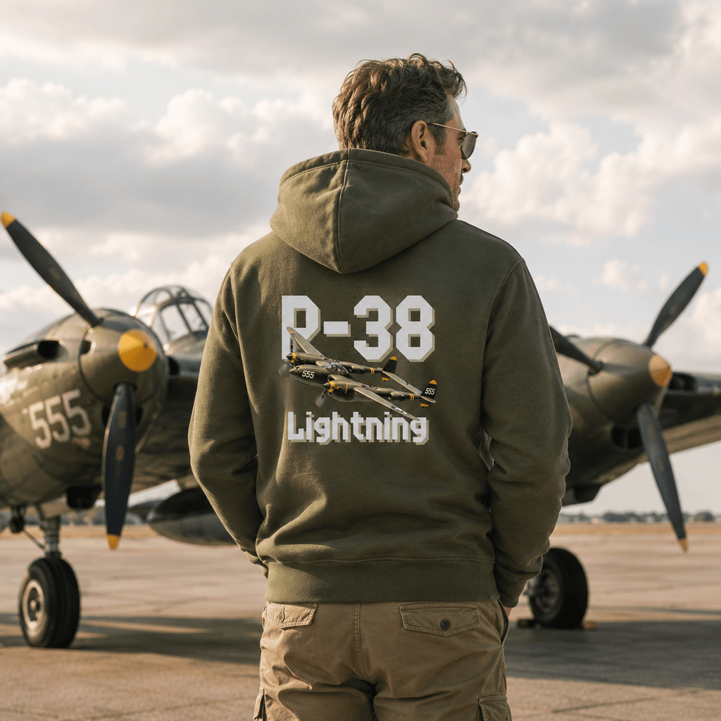Man wearing a green hoodie with 'P-38 Lightning' design in front of vintage airplanes.