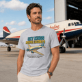 Man wearing a t-shirt with 'Sky Kings Route Escobar' design in front of an airplane.