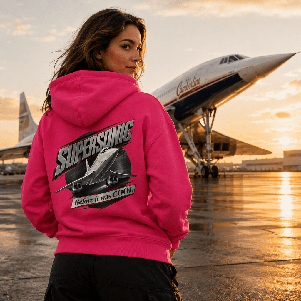 Person wearing a pink hoodie with 'Supersonic Before it was Cool' design in front of an airplane.