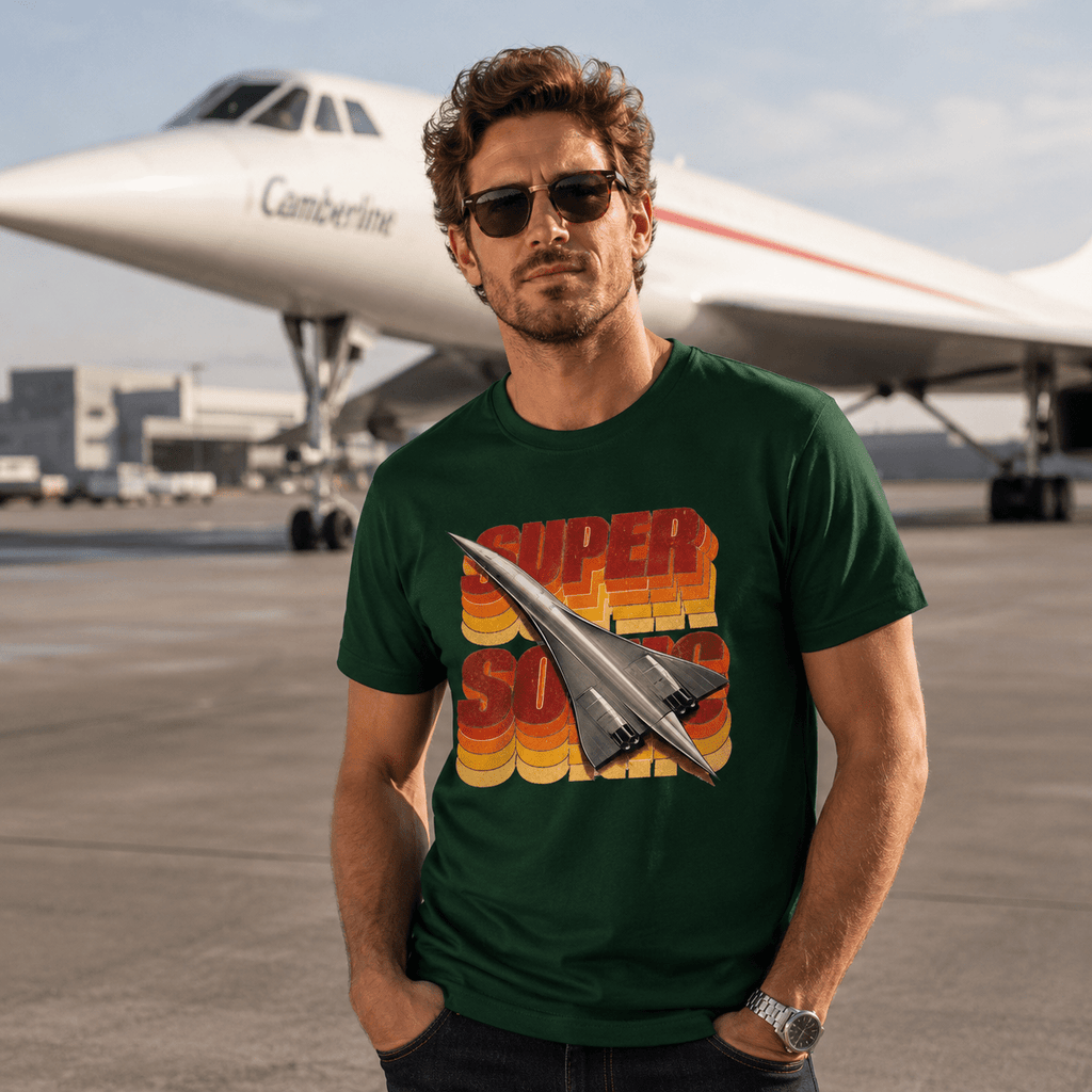 Man outdoors wearing a forest green Camberline t-shirt featuring a supersonic delta jet graphic.