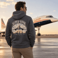 Person wearing a hoodie with 'Super-Sonic' design in front of an airplane on a runway.