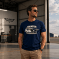 Man wearing a navy blue t-shirt with a graphic design in an airplane hangar.