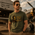 Man wearing a green t-shirt with a vintage airplane graphic and text, standing in front of an airplane at an airfield.