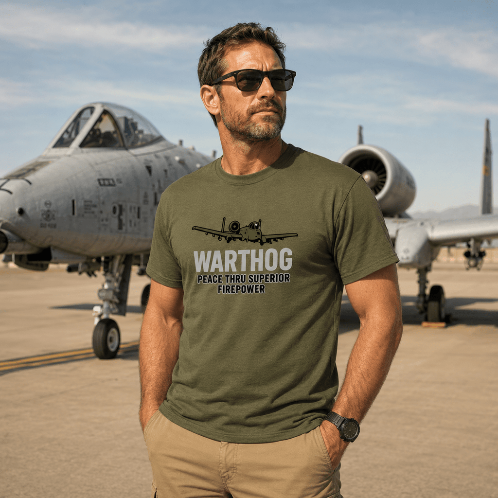 Man wearing a green t-shirt with 'Warthog' design in front of an airplane on a runway.