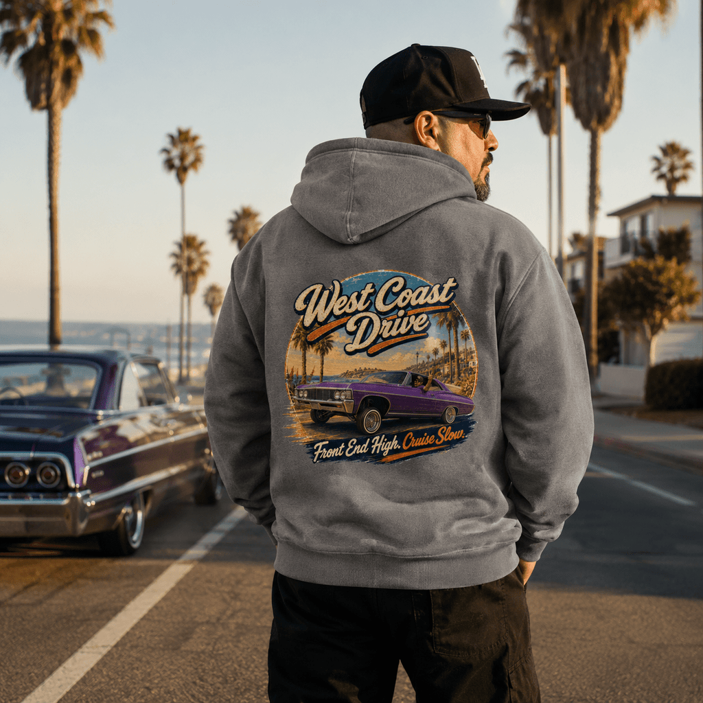 Model wearing the Camberline Cars West Coast Drive Lowrider Hoodie – Heather Grey, showing the automotive graphic in a car culture setting