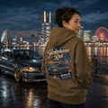Model wearing the Camberline Cars Yokohama Run Hot Hatch Hoodie – Combat Green, showing the automotive graphic in a car culture setting