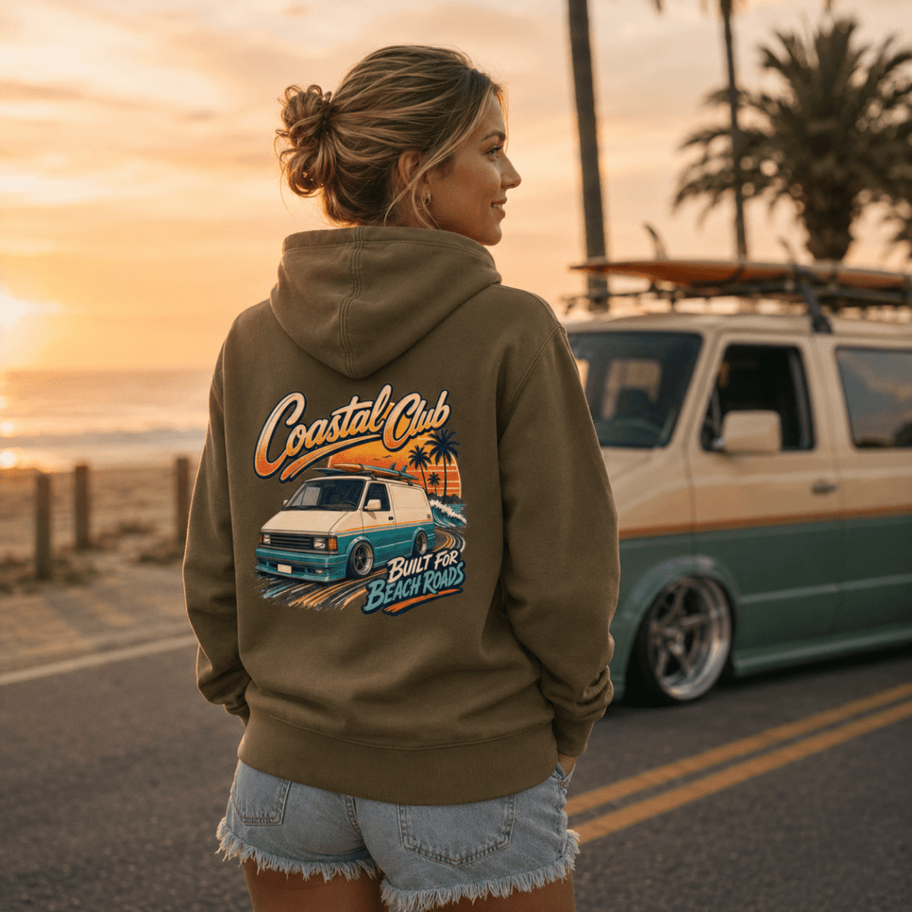 Model wearing Camberline olive van life hoodie showing Coastal Club Built for Beach Roads slammed retro van and palm tree sunset on back