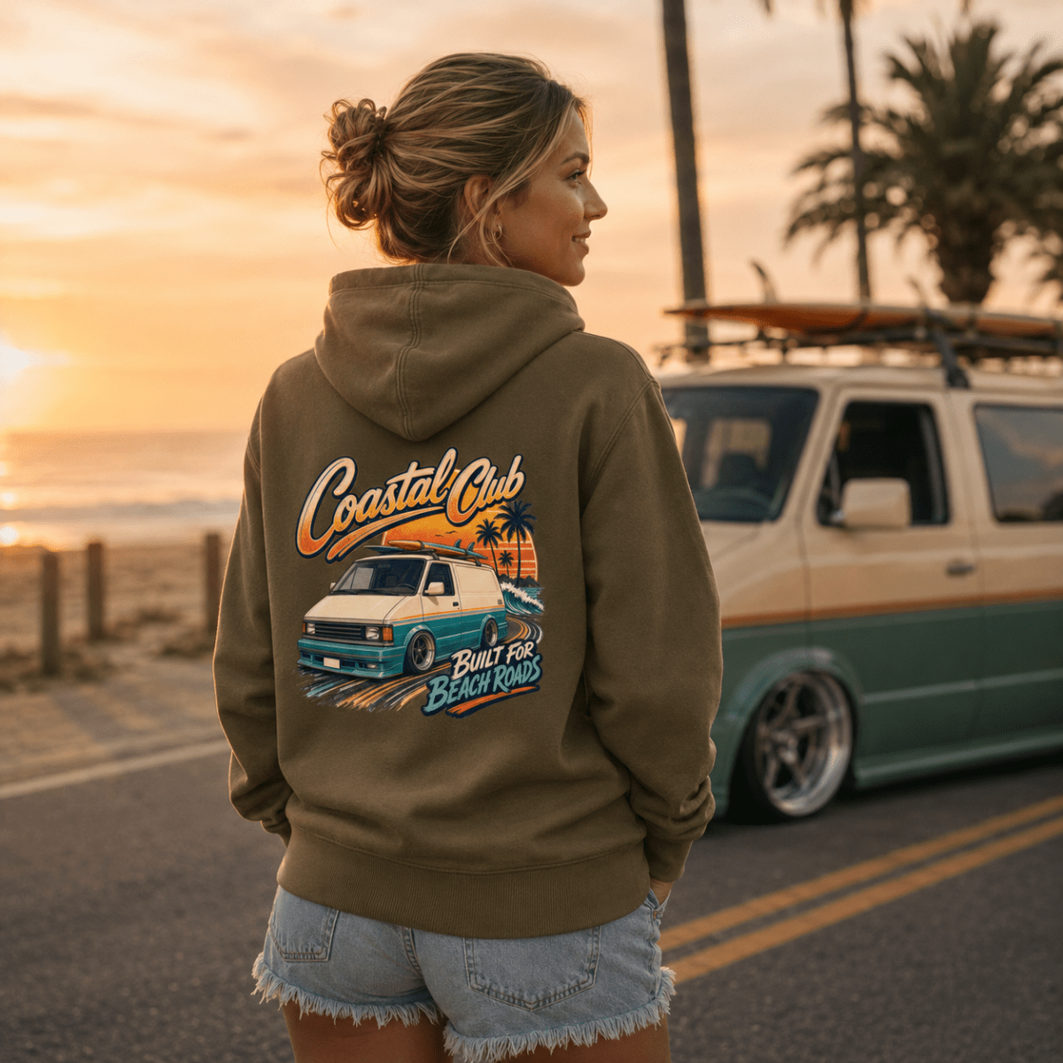 Model wearing Camberline olive van life hoodie showing Coastal Club Built for Beach Roads slammed retro van and palm tree sunset on back
