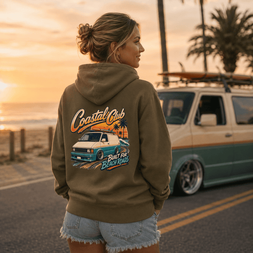 Model wearing Camberline olive van life hoodie showing Coastal Club Built for Beach Roads slammed retro van and palm tree sunset on back