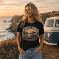 Model wearing Camberline black van life t-shirt showing Coastal Nomad Cornwall Weekender retro split-screen van Cornish clifftop badge on chest