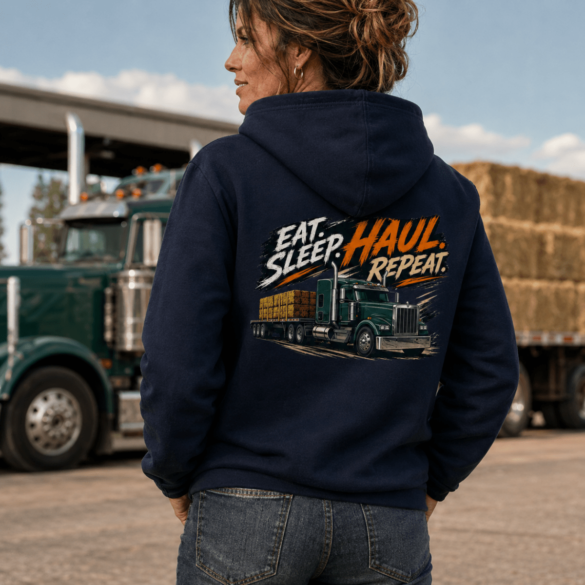 Person wearing a hoodie with 'Eat. Sleep. Haul. Repeat.' text and truck graphic, standing in front of a truck.