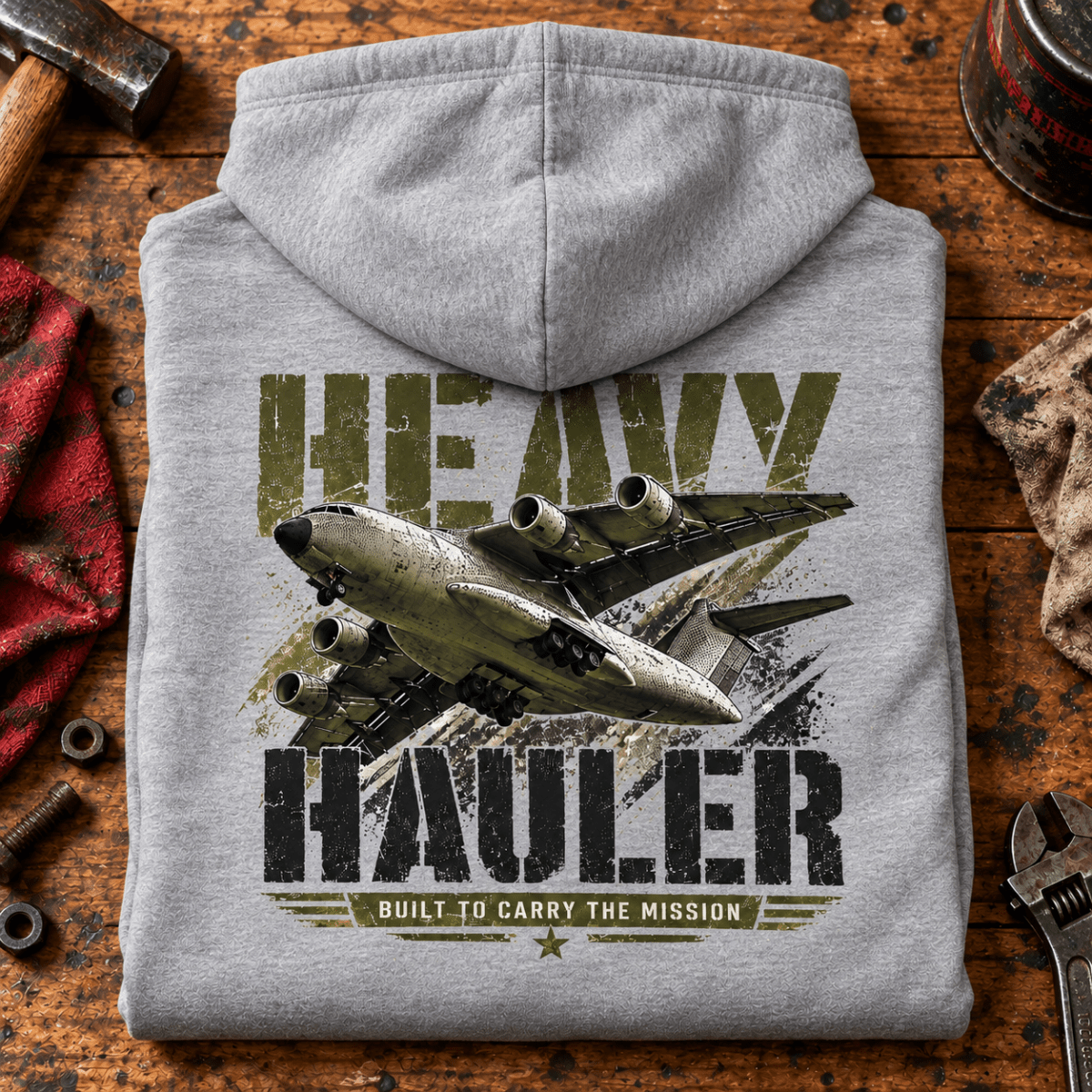 Heavy Hauler Transport Aircraft hoodie in Sport Grey (Heather Grey), folded on a workshop bench, showing the back print