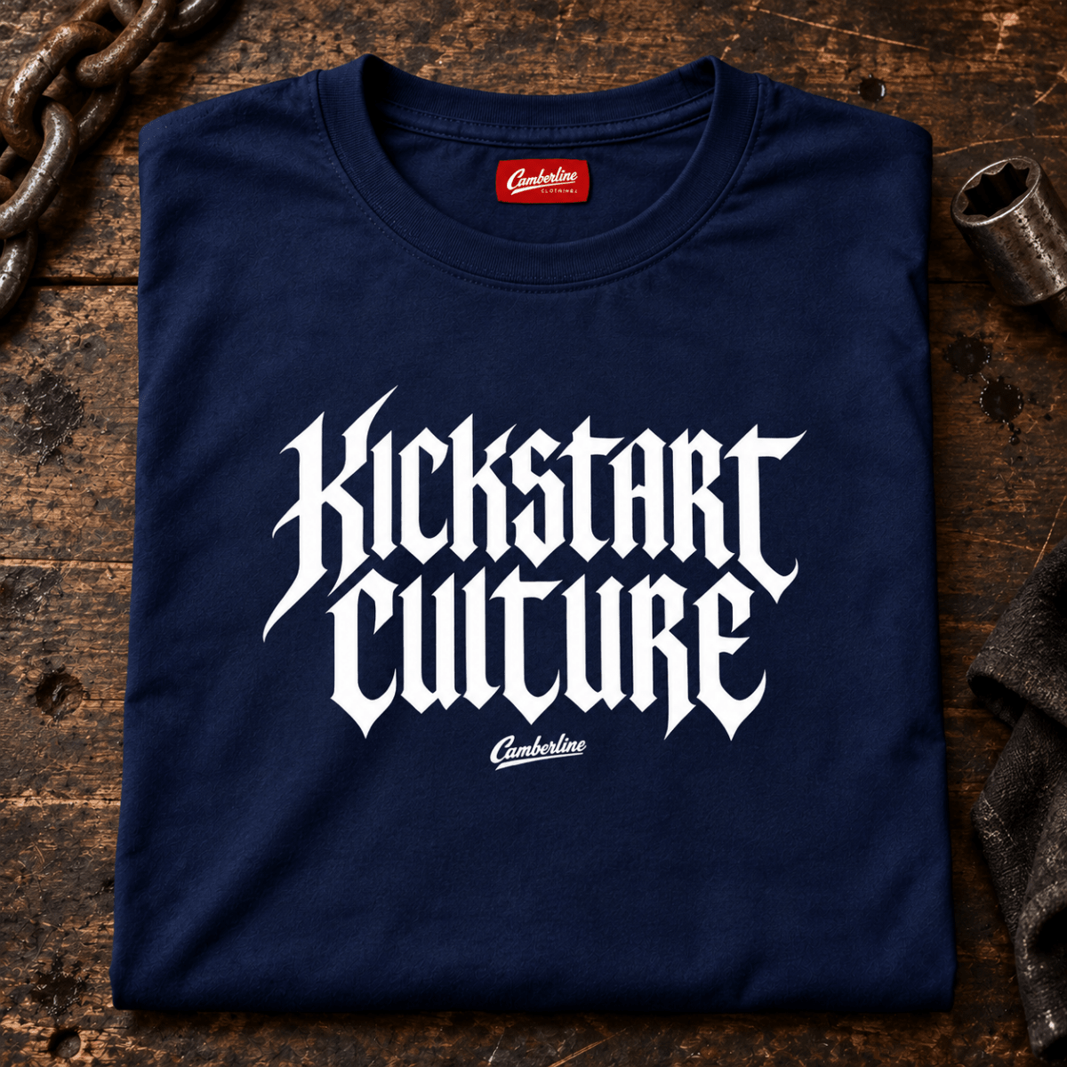 Camberline Kickstart Culture Gothic navy motorcycle T-shirt front print on a stripped-back workshop bench