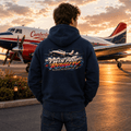 Person wearing a hoodie with 'Twin Prop Royalty' design, standing on an airport tarmac with an airplane in the background.