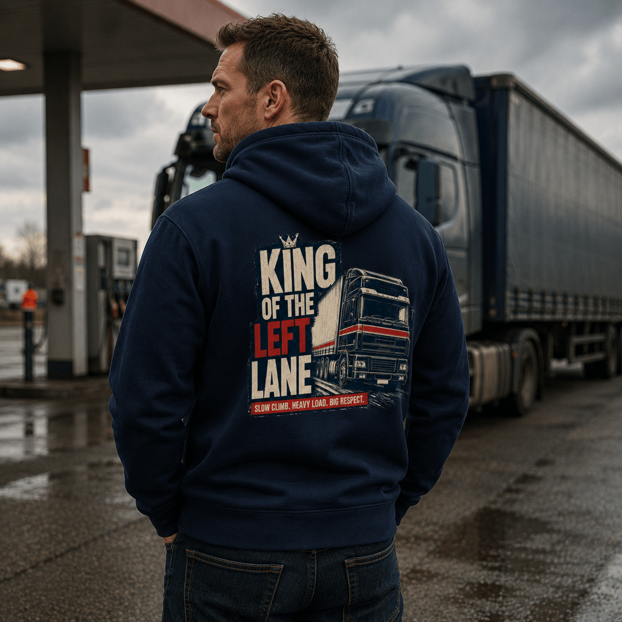 Man wearing a navy blue hoodie featuring a distressed graphic of a black and red European lorry with the text King of the Left Lane and Slow climb Heavy load Big respect.