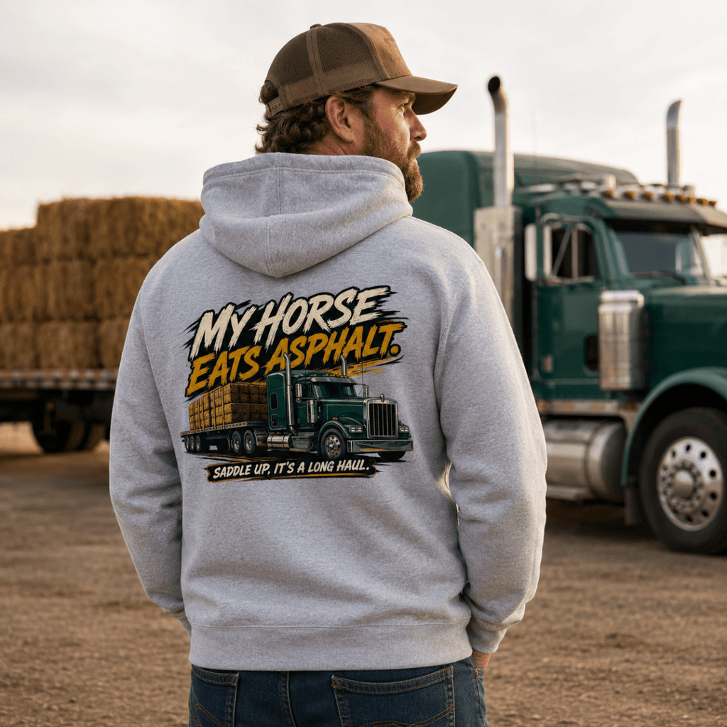 Man wearing a hoodie with a truck graphic and text, standing in front of a large truck.