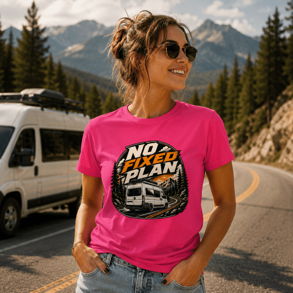 Model wearing Camberline pink van life t-shirt showing No Fixed Plan circular badge with rear-view high-roof van on mountain road on chest