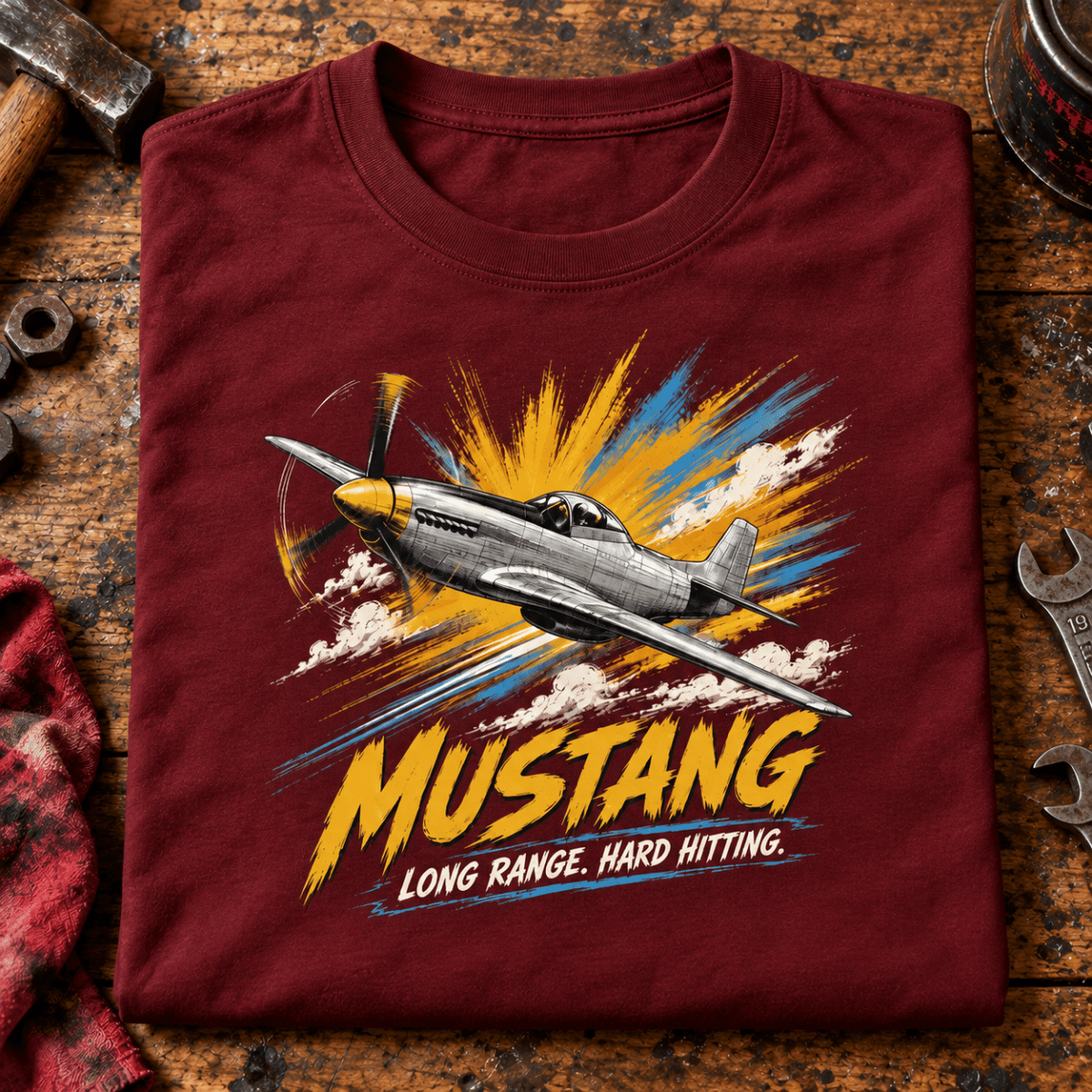 P-51 Mustang Fighter t-shirt in Burgundy, folded on a workshop bench, showing the front print