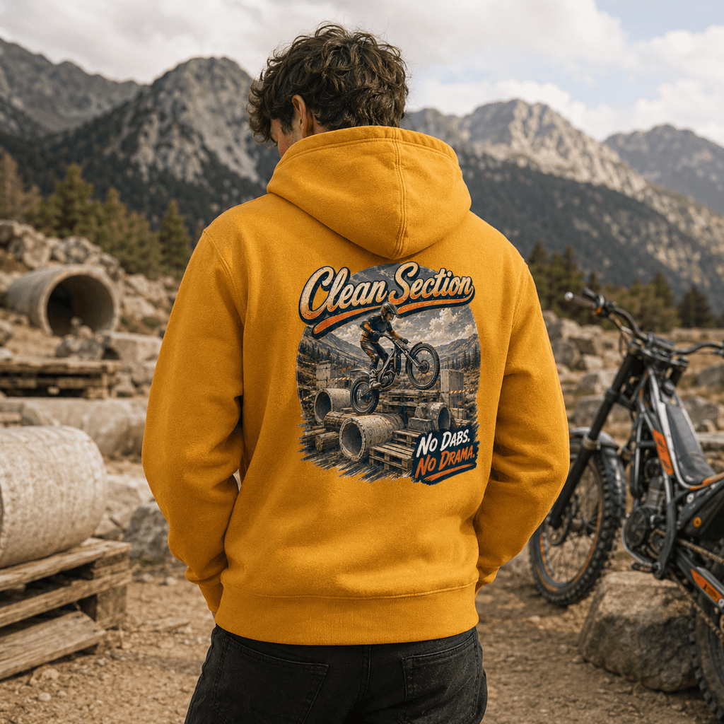 Model wearing the Camberline Riders Clean Section Trials Bike Hoodie – Mustard, showing the Riders back graphic in a motorcycle-inspired setting