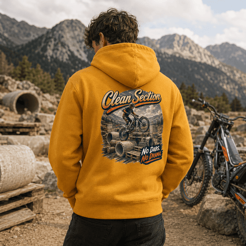 Model wearing the Camberline Riders Clean Section Trials Bike Hoodie – Mustard, showing the Riders back graphic in a motorcycle-inspired setting