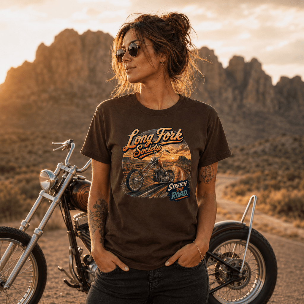 Model wearing the Camberline Riders Long Fork Society Chopper T-Shirt – Dark Chocolate, showing the Camberline Riders graphic in a motorcycle-inspired setting