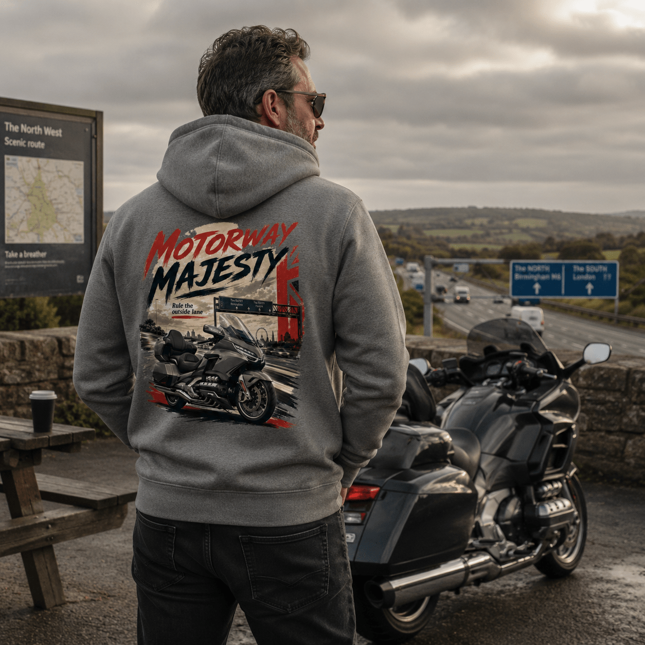 Model wearing the Camberline Riders Motorway Majesty Heavy Tourer Hoodie – Charcoal, showing the Camberline Riders graphic in a motorcycle-inspired setting
