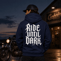 Model wearing the Camberline Riders Ride Until Dark Gothic Typography Hoodie – Navy, showing the Riders back graphic in a motorcycle-inspired setting