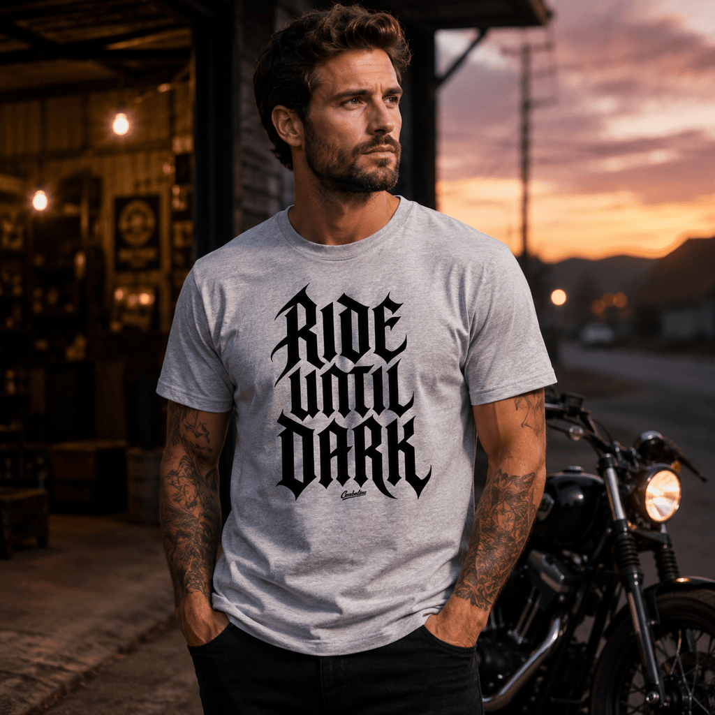 Model wearing the Camberline Riders Ride Until Dark Gothic Typography T-Shirt – Grey, showing the Riders front graphic in a motorcycle-inspired setting