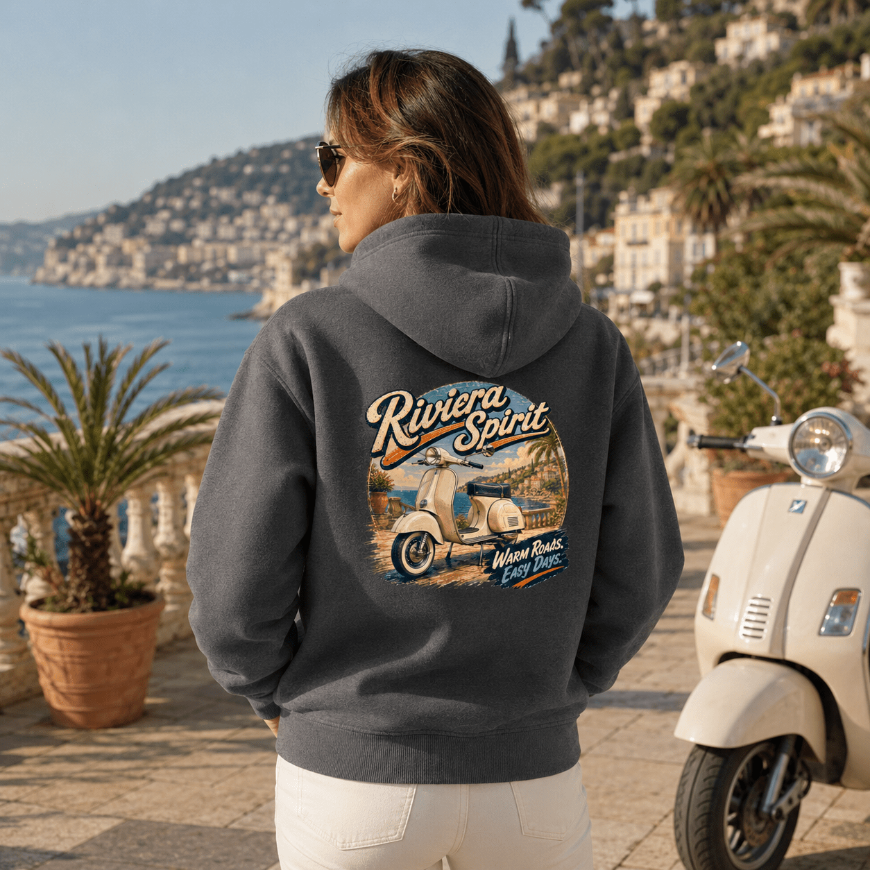 Model wearing the Camberline Riders Riviera Spirit Retro Scooter Hoodie – Charcoal, showing the Camberline Riders graphic in a motorcycle-inspired setting