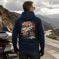 Model wearing the Camberline Riders The Long Hauler Touring Motorcycle Hoodie – Navy, showing the Riders back graphic in a motorcycle-inspired setting
