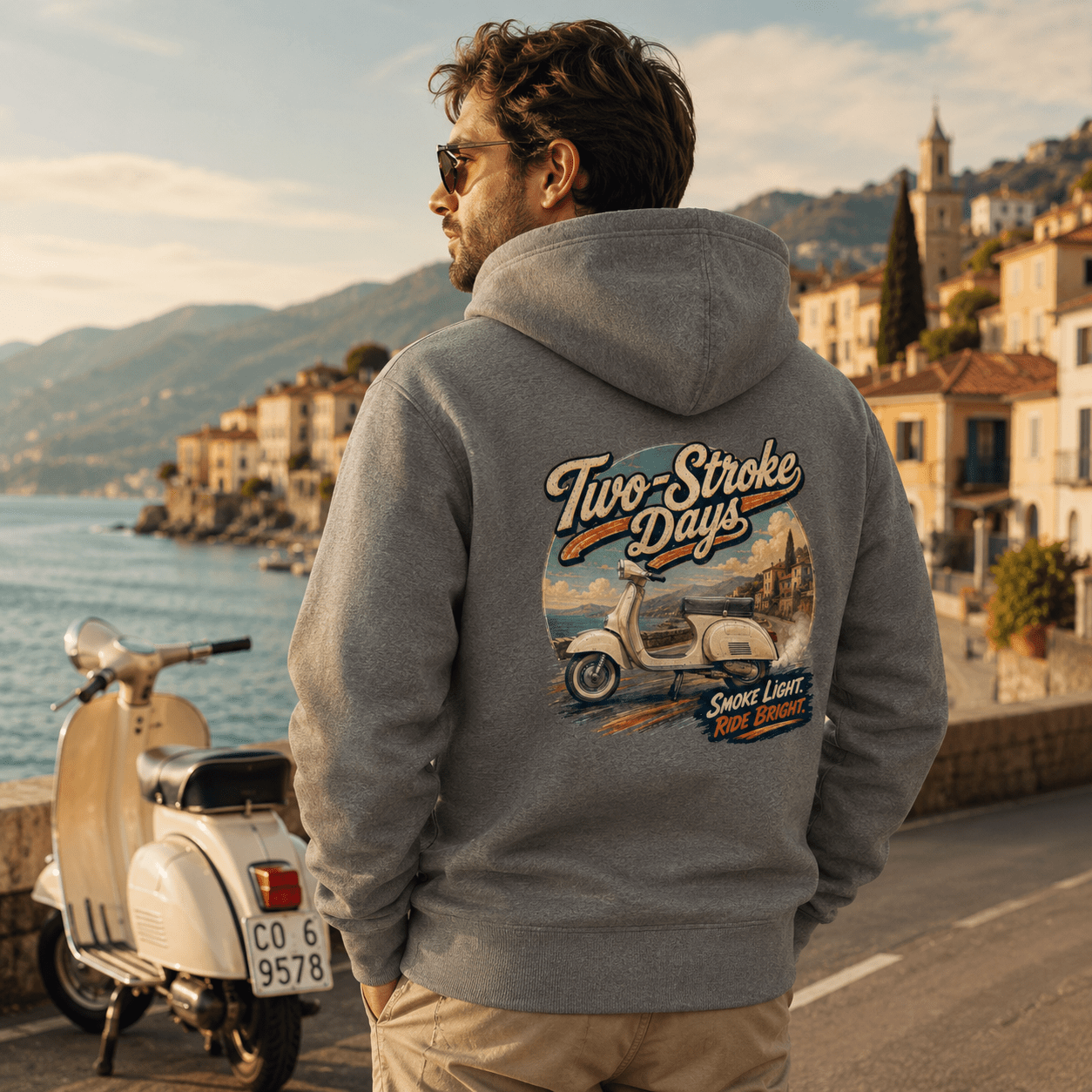 Model wearing the Camberline Riders Two Stroke Days Vintage Scooter Hoodie – Charcoal, showing the Riders back graphic in a motorcycle-inspired setting