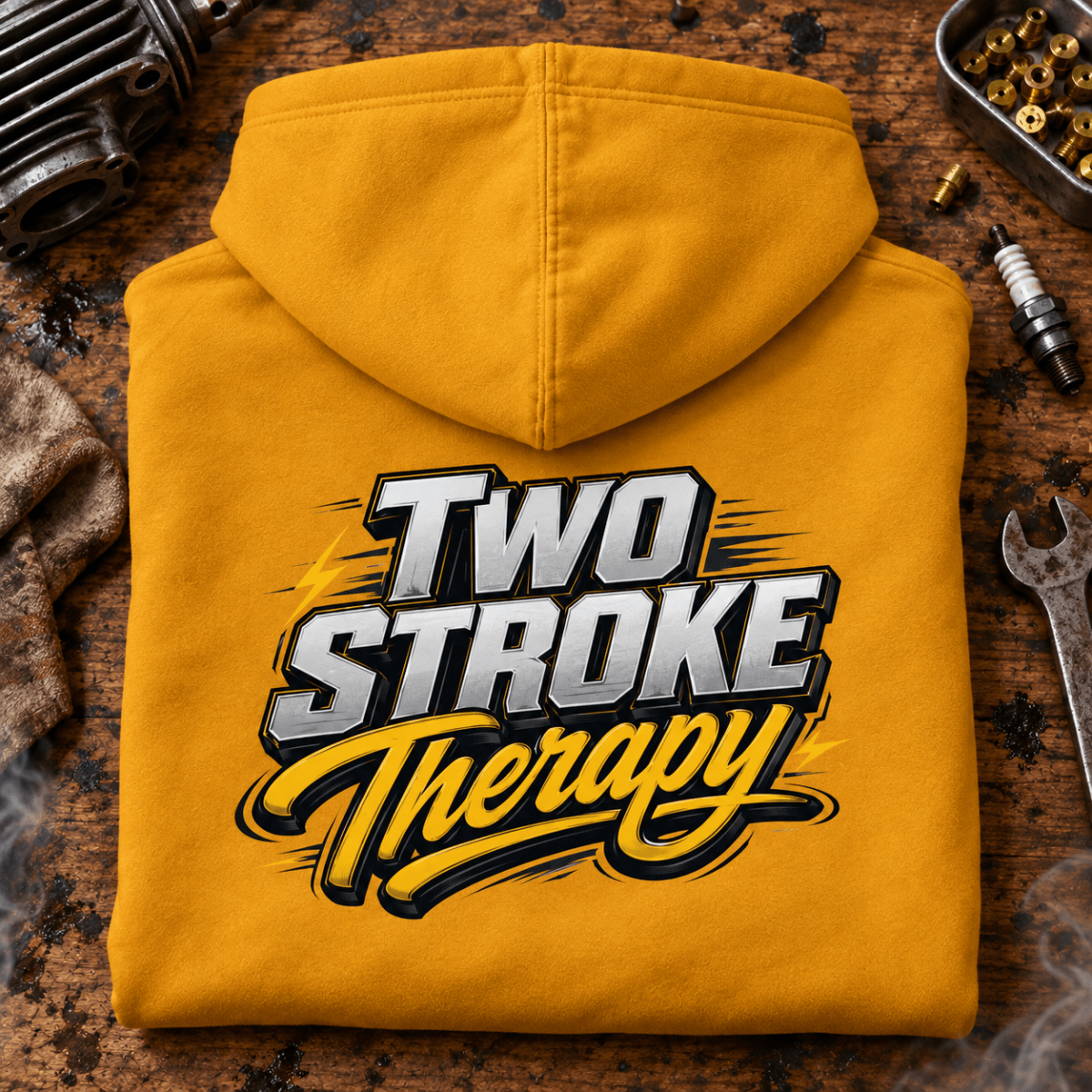 Camberline Two Stroke Therapy mustard motorcycle hoodie back print on a gritty two-stroke workshop bench