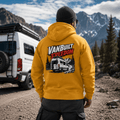 Model wearing Camberline amber/mustard van life hoodie showing VanBuilt Freedom rear-view high-roof van with ladder on mountain road on back