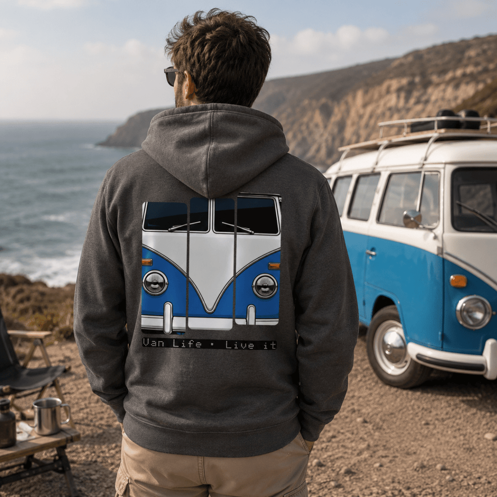 Person wearing a hoodie with a van design, standing near a blue and white van by the ocean.
