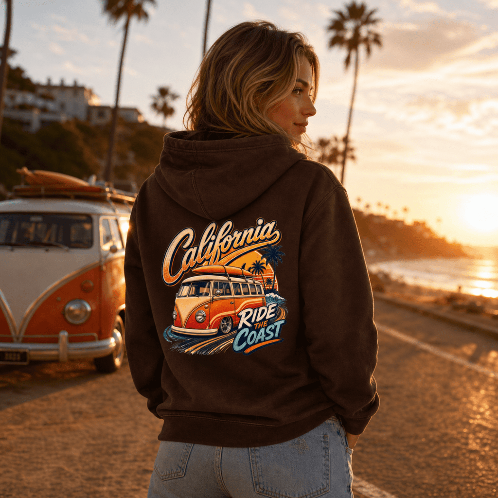 Person wearing a hoodie with a 'California Ride the Coast' design, standing near a vintage van by a beach at sunset.