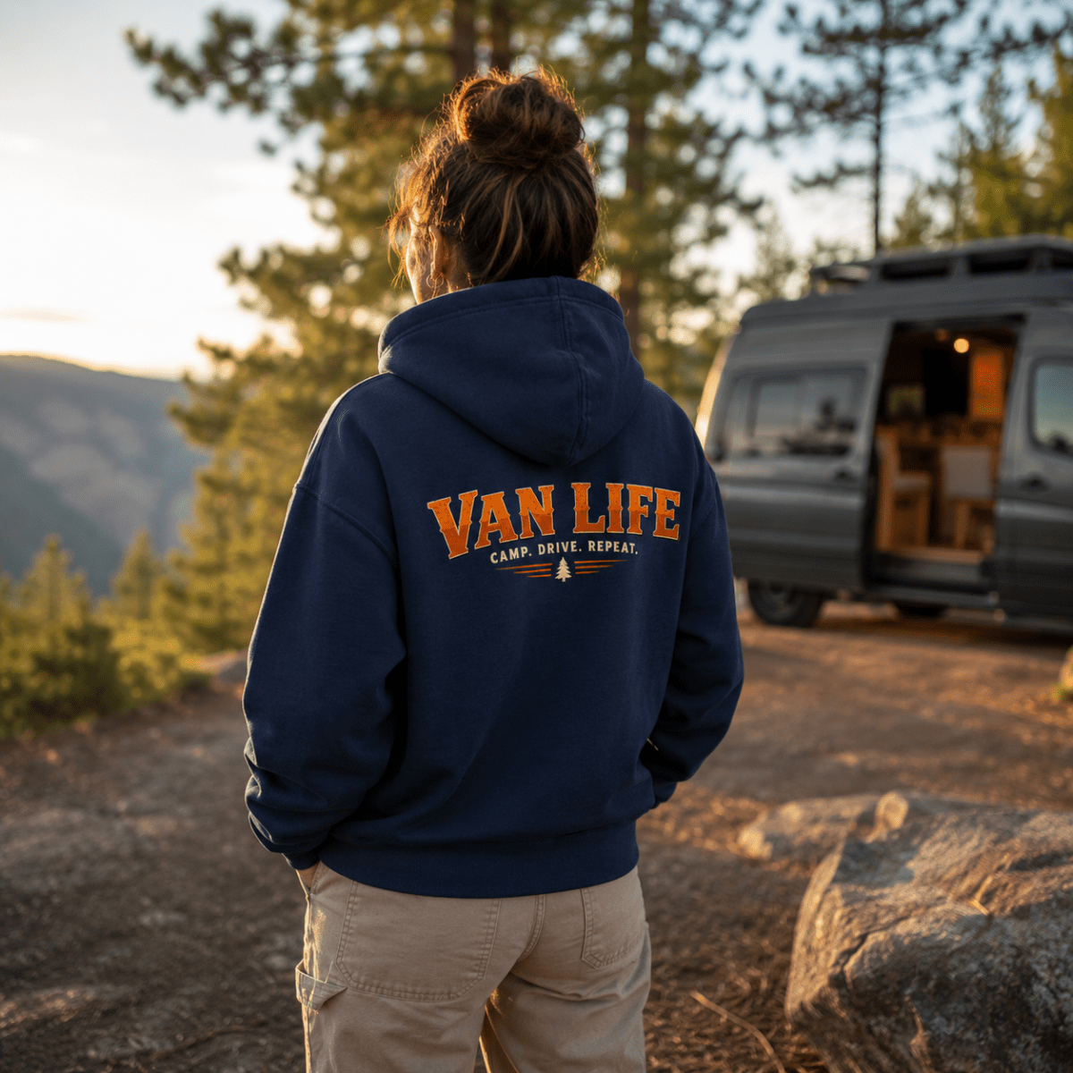 Camberline Van Life Camp Drive Repeat navy hoodie worn by female model at mountain viewpoint with converted campervan in background