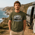 Man wearing a 'Coastal Escape Van Life Society' t-shirt standing near a van by the ocean.