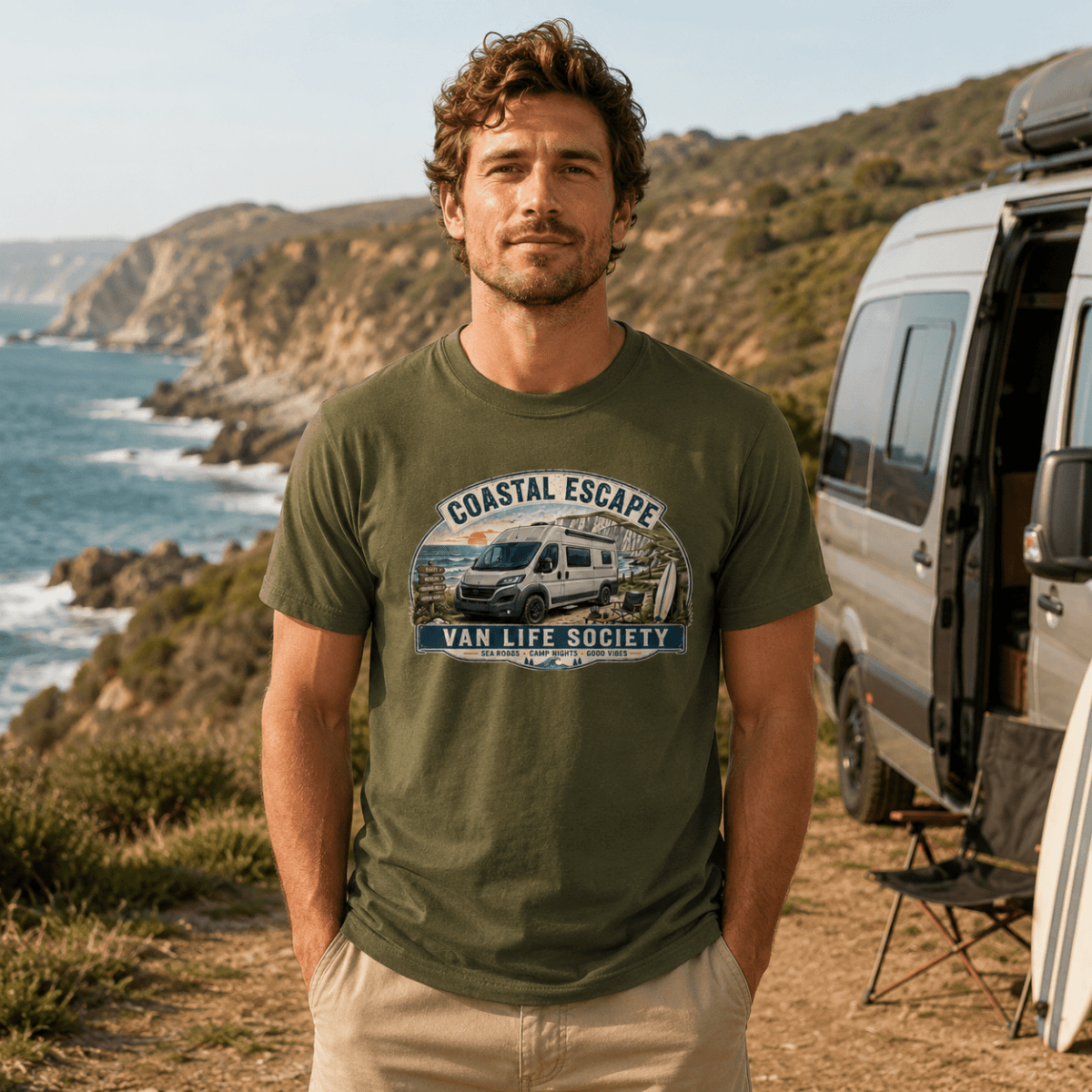 Man wearing a 'Coastal Escape Van Life Society' t-shirt standing near a van by the ocean.