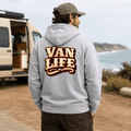 Model wearing Camberline chocolate brown van life hoodie showing Van Life collegiate VAN LIFE wordmark in cream and orange on back