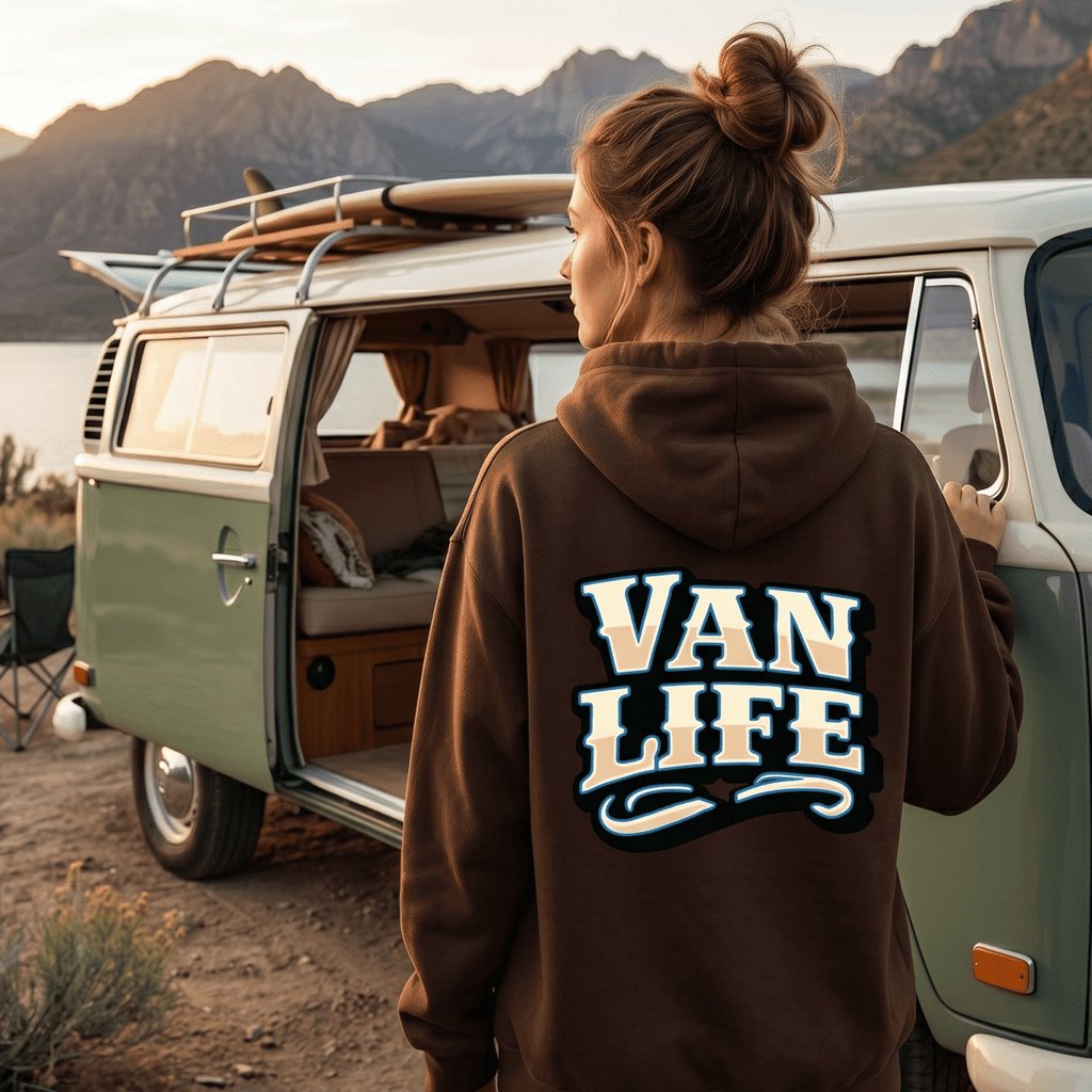 Person wearing a 'Van Life' hoodie standing next to a vintage van with mountains in the background