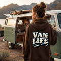 Person wearing a 'Van Life' hoodie standing next to a vintage van with mountains in the background