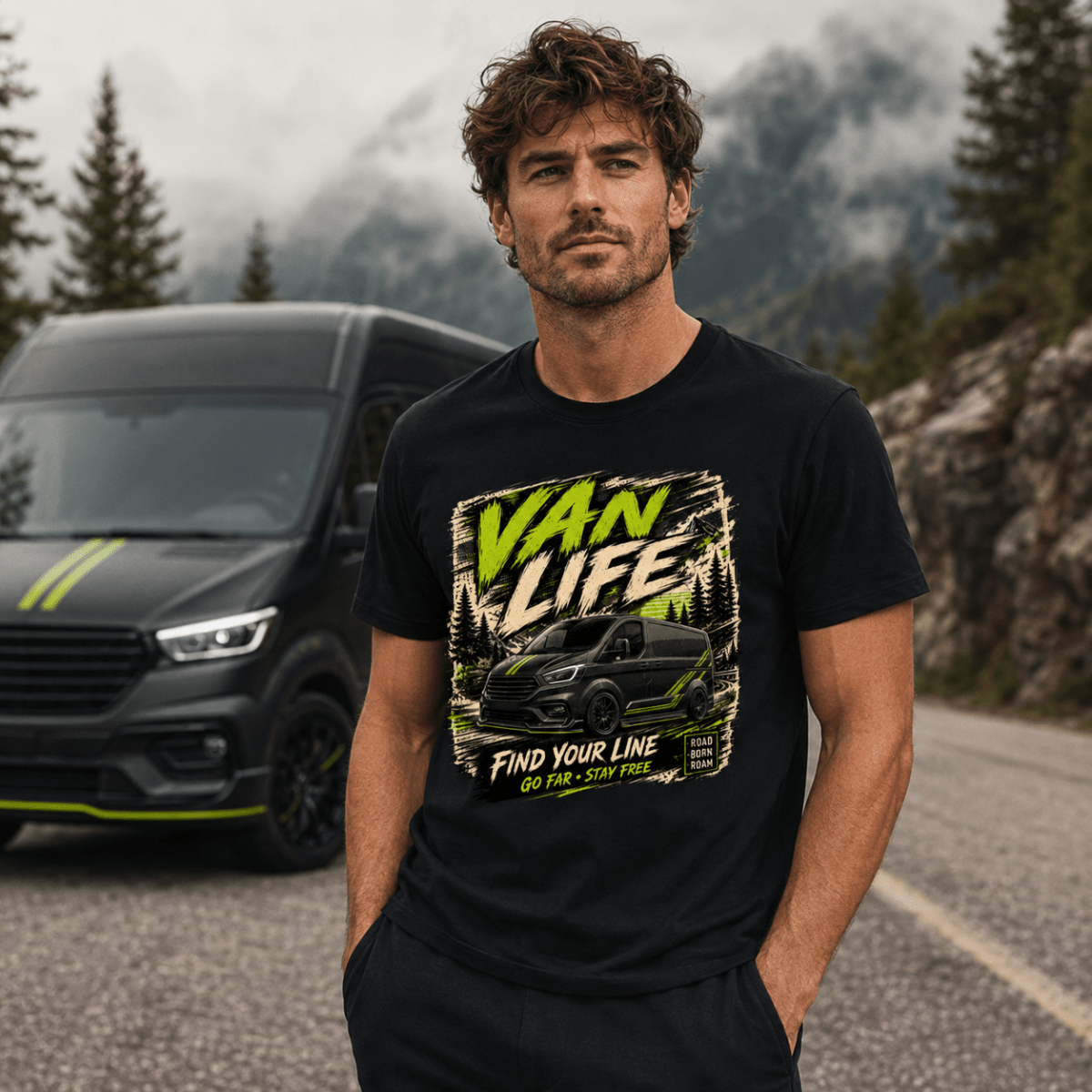Man wearing a black t-shirt with 'Van Life' graphic in front of a black van on a mountain road.